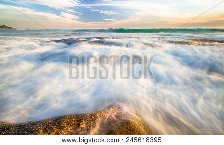 Long Exposure Of Ocean Waves Flowing Over Rocky Tidepools At Sunset On Johanna Beach In The Great Ot