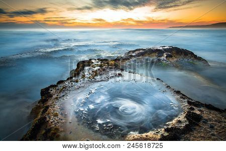 Long Exposure Of Ocean Waves Flowing Over Rocky Tidepools At Sunset On Johanna Beach In The Great Ot