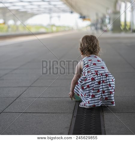 Little Girl Child In A Dress Playing With A Ball On A Deserted Railway Perron