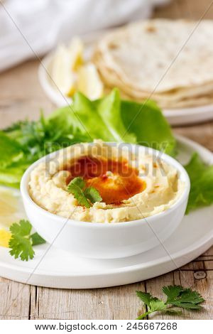 Hummus With Olive Oil And Paprika, Served With Pita, Lemon And Lettuce Leaves. Selective Focus.