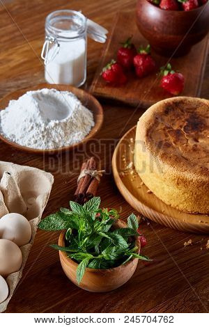 Top View Raw Ingredients For Cooking Strawberry Pie Or Cake On Wooden Table: Eggs, Sugar And Strawbe