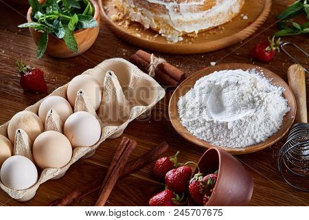 Top View Raw Ingredients For Cooking Strawberry Pie Or Cake On Wooden Table: Eggs, Sugar And Strawbe