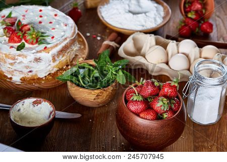 Top View Raw Ingredients For Cooking Strawberry Pie Or Cake On Wooden Table: Eggs, Sugar, Mint And S