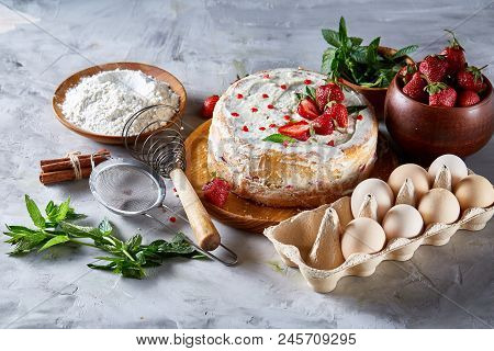 Strawberry Tart Covered With Whipped Sour Cream Surrounded By Organic Ingredients Over White Backgro