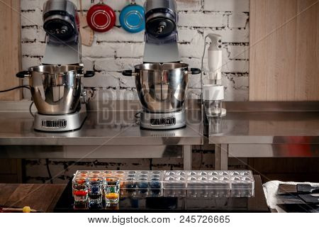 Confectionery And Cooking Tools For Sweets On Wooden Table. Plastic Moulds, Mixers, Food Colors, Mea