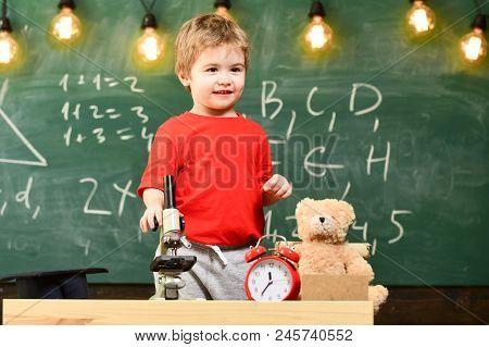 Child, Pupil On Calm Face Near Microscope. Kid Boy Near Microscope In Classroom, Chalkboard On Backg