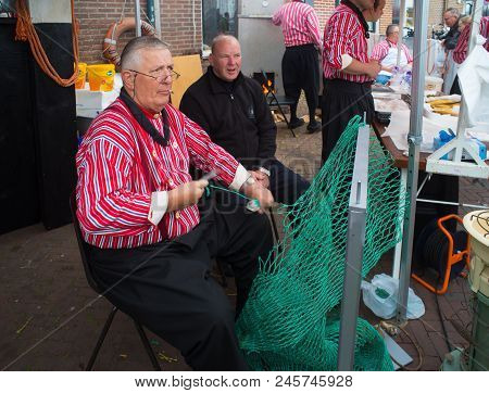 Urk, Netherlands - May 19, 2018: Unknown Man In Traditional Clothes Making Fishing Nets On The Urker