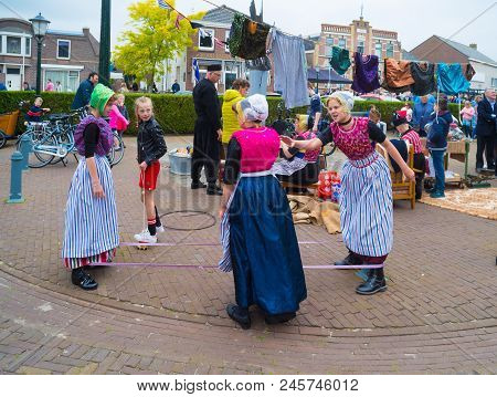Urk, Netherlands - May 19, 2018: Unknown Girls In Traditional Costumes Playing An Old-fashioned Stri