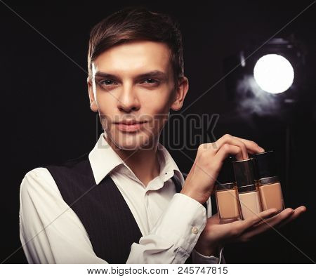 Beauty concept. Young male make up artist posing with foundation for make-up d.