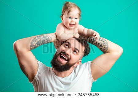Portarit Of Amasing Caucasian Infant Baby Laughing In Delight While Sitting Om Daddys Neck. Happy Ha