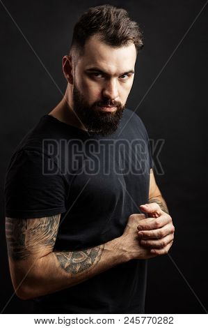 Confident Serious Man In Black Tight T-shirt Standing Against Black Background At Studio