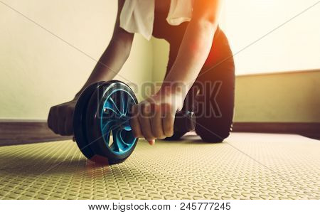 Attractive Woman With Abdominal Exercises With Wheel. Workout At Home To Lose Weight Indoor Room