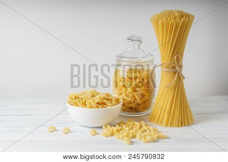 Different Kinds Of Pasta And Spagetty Bunch On White Wood Table.
