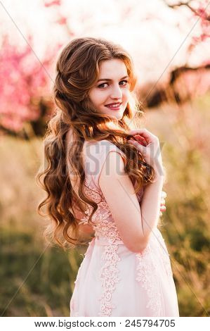A Girl Is Walking Among The Blooming Peaches