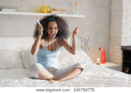 Happy Young Latina Woman Holding Pregnancy Test Kit, Waiting For Result. Euphoric Hispanic Girl Smil