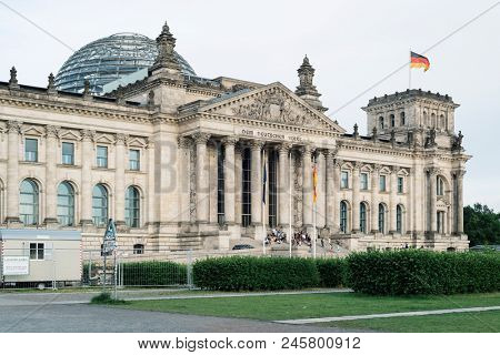 BERLIN, GERMANY - MAY 23, 2018: A view of the main facade of the Reichstag building in Berlin, Germany, with some visitors in the staircase, seen from Platz der Republik square