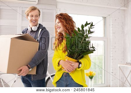 Lovely Roommate. Gay Attractive Couple Holding Belongings And Bursting From Laughing