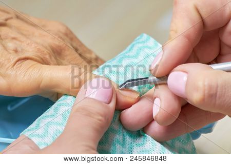 Manicurist Cut The Cuticle To The Client. Nail Beautician Cutting The Cuticle Using Cuticle Scissors