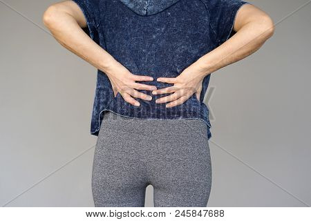 Close-up View Of A Young Woman With Pain In Kidneys Isolated On A Gray Background. Young Woman With 