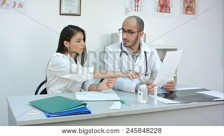 Doctor Showing His Female Trainee How To Read Cardiogram While
