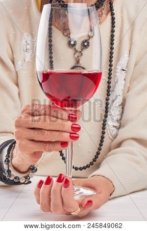 Large Glass Of Wine In Female Hands. Woman Hands With Red Manicure Holding Glass Of Wine Close Up. G