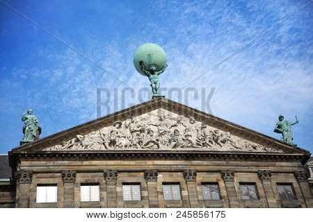 The facade and statues of the 17th century Royal Palace of Amsterdam, otherwise known as the Dam Palace, in Amsterdam, Netherlands. Atlas is seen holding the world on his shoulders in the centre.