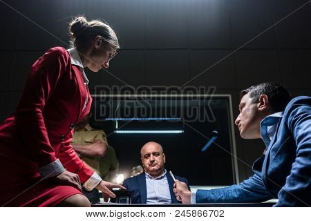 Low-angle view of a female attorney in disagreement with the prosecutor, during the preliminary hearing of an unwilling suspect in the office of a police station