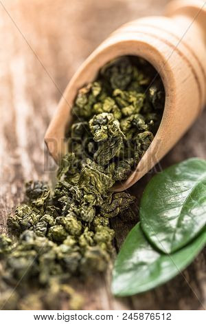 Spoon Of Dried Green Tea Leaves On Wooden Background. Leaves Of Green Tea Close Up