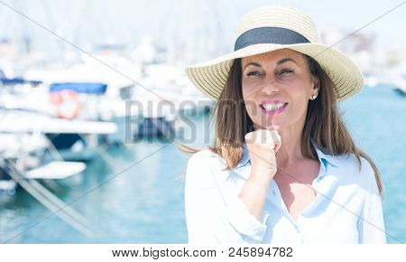 Beautiful middle age woman standing with the sea in the background serious face thinking about question, very confused idea