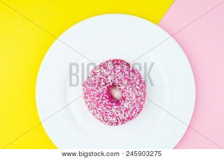 Tasty Donut With Topping On Pastel Pink And Yellow Background.