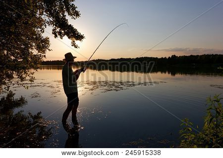 Silhouette Of Isherman Catching The Fish During Sunset