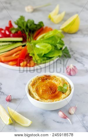 Hummus, Different Vegetables And Lettuce Leaves With Lemon And Garlic On A Light Background. Vegan F