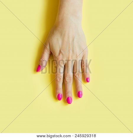 Female Hand With Pink Nail On Yellow. Concept.
