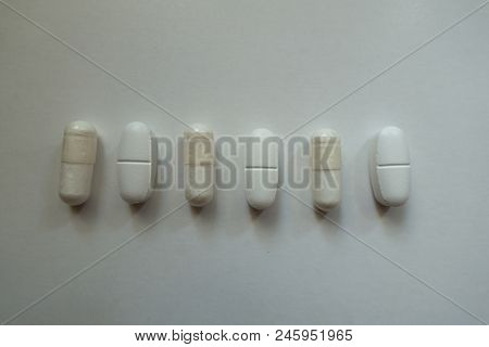 White Capsules Of Magnesium Citrate And Caplets Of Calcium Citrate In A Row From Above