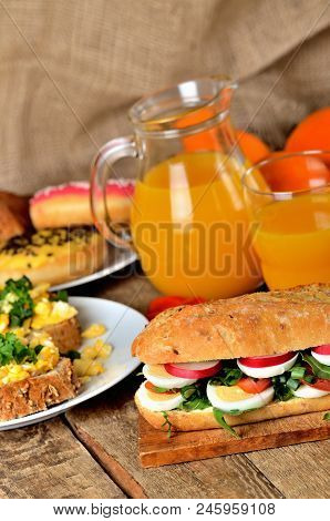 Large Baguette Sandwich Cut In Half Filled With Hard-boiled Egg, Arugula Salad, Tomatoes And Radish 
