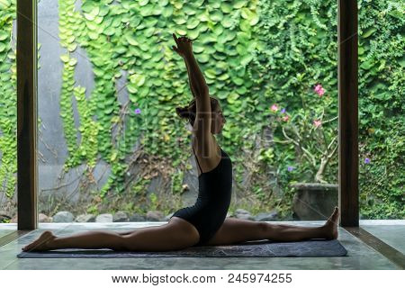 Side View Of Beautiful Young Woman Practicing Yoga In Front Splits Pose Hanumanasana In Front Of Wal