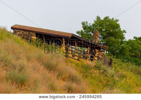 Wooden Gazebo With Wooden Table And Chairs In The Autumn Park With Birch And Pine Trees.