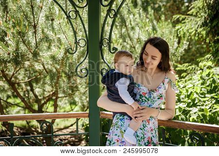 Happy Mother Hugging Her Little Son In The Summer Outdoor At The Park