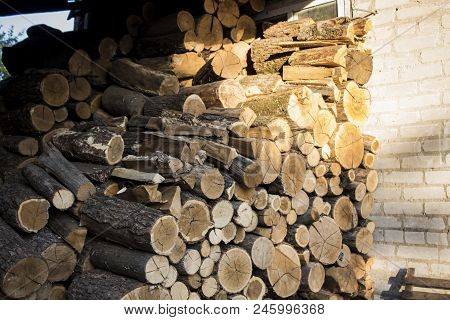 A Pile Of Stacked Firewood, Prepared For Heating The House. Firewood Harvested For Heating In Winter