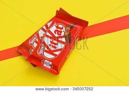 Kit Kat Chocolate Bars In Red Wrapping Lies On Yellow And Red Background. Kit Kat Created By Rowntre