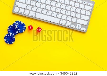 Hazard Gemes Online Concept. Chips And Dices Near Keyboard On Yellow Background Top-down Copy Space