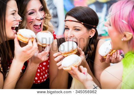 Happy girls at German Fasching Carnival eating doughnut-like traditional pastry