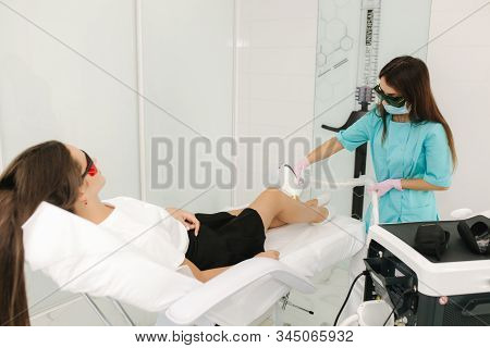Young Woman Getting Laser Treatment On Leg At Spa. Laser Epilation And Cosmetology