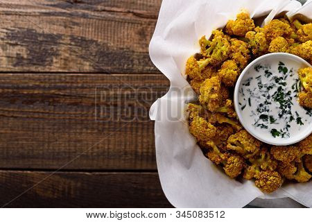 Top View Of Baked Cauliflower With Sauce And Greens On Wooden Background With Copy Space