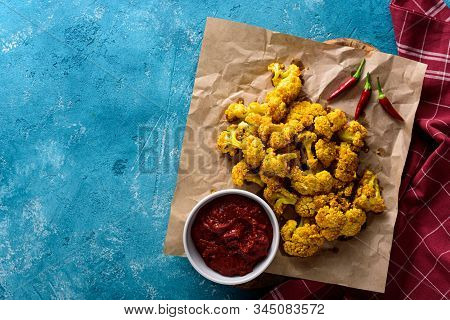 Top View Of Baked Cauliflower With Chili Sauce And Pepper On Blue Background With Copy Space