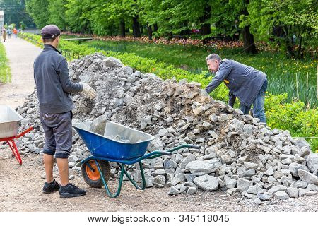 Moscow,russia,july 27, 2019:two Workers Load Stones Into A Wheelbarrow During The Repair Of The Side