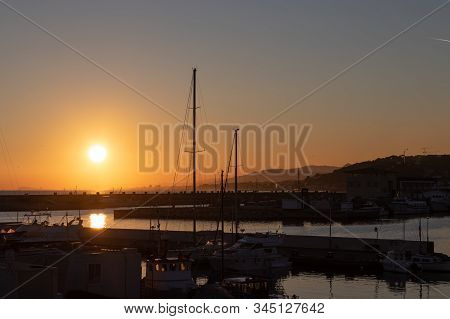 Dramatic Sunset Seen From A Harbor With Multiple Sailboats And Ships