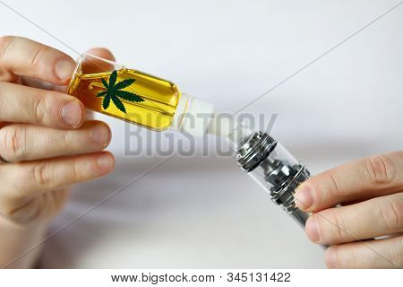 Male Hand Fill Up Liquid Organic Extra Virgin Cannabinoid Oil With Vipe Pen System Against Home Back