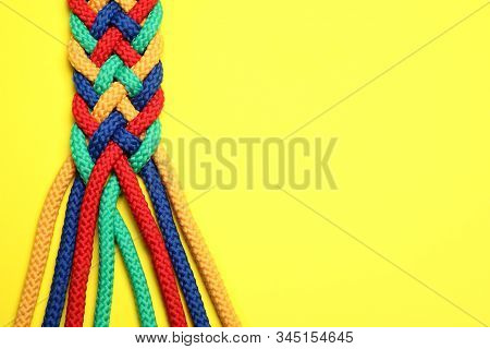 Top View Of Braided Colorful Ropes On Yellow Background, Space For Text. Unity Concept