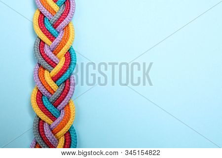Top View Of Braided Colorful Ropes On Light Blue Background, Space For Text. Unity Concept